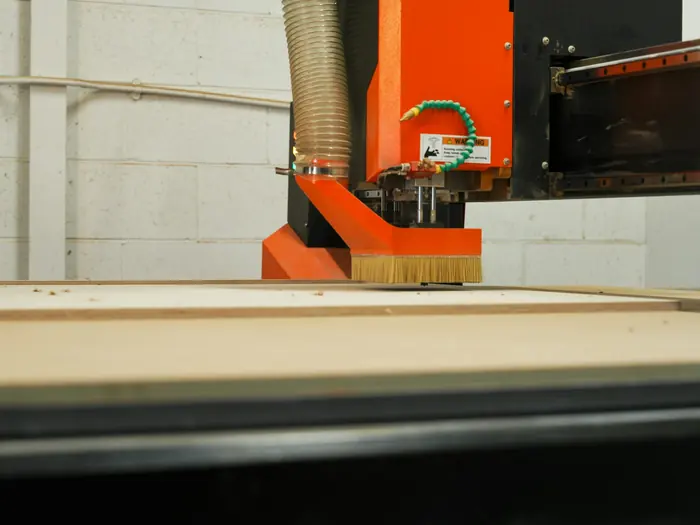 CNC machine cutting a wooden panel in a furniture workshop