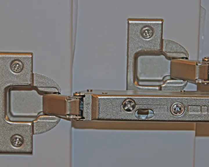 Two 35 mm concealed hinges with clip-on plates fitted to white cabinet doors
