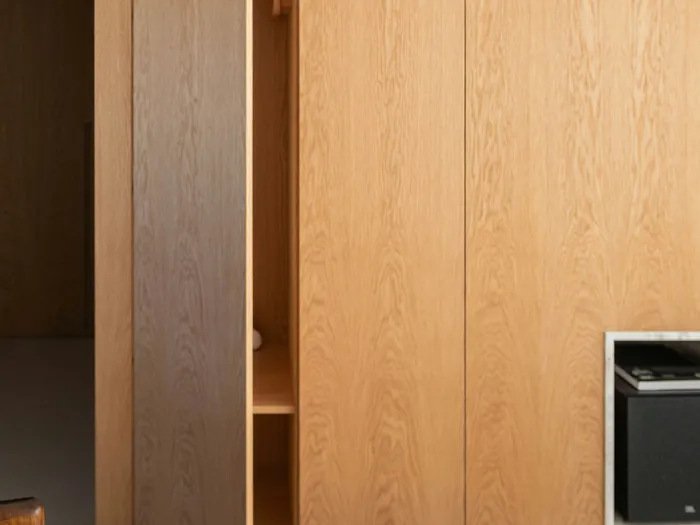 Tall oak cabinet with one slab door open, the door covering the cabinet side