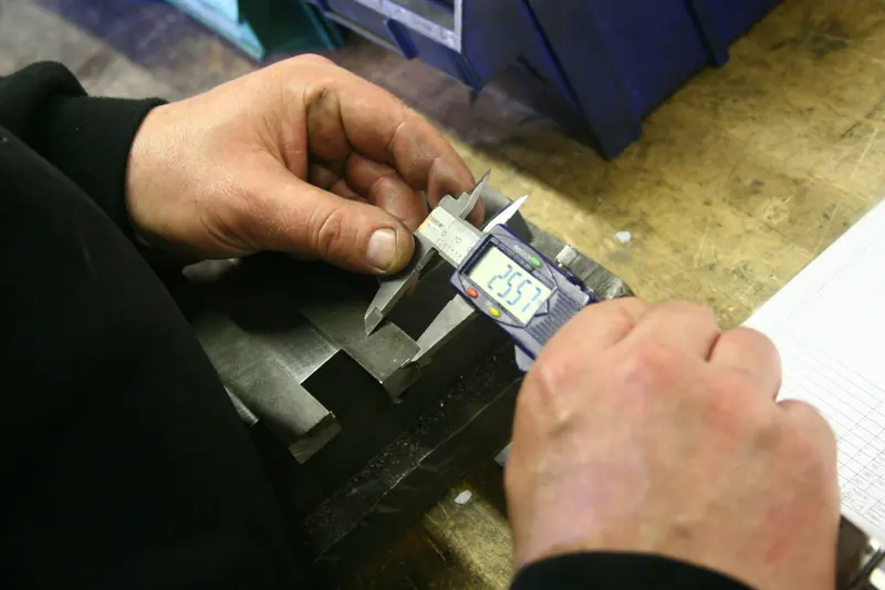 Hands measuring a metal part with a digital caliper