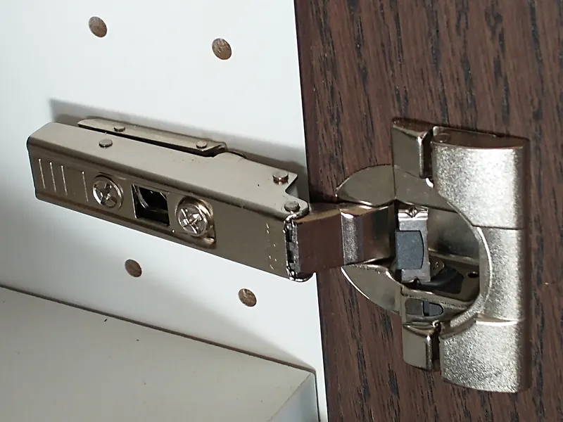 Concealed hinge with a clip-on plate mounted on a dark solid wood door